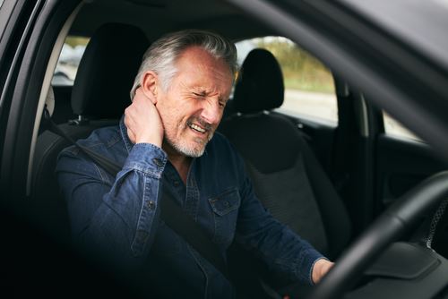 A man holding his hurt neck after a car accident